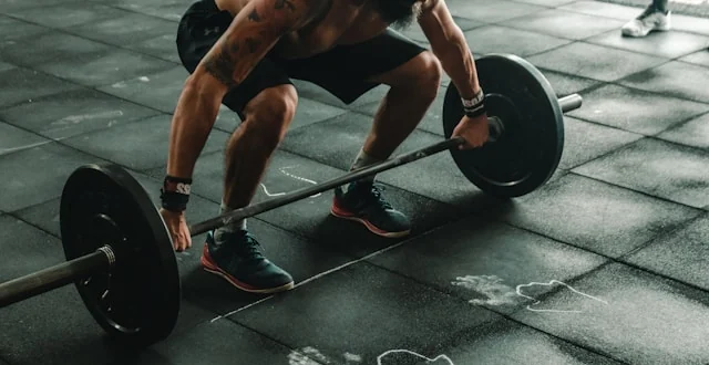 Homme s'apprêtant à soulever une barre chargée dans une salle de sport